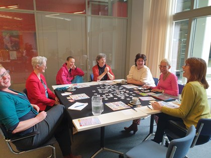 Een aantal mensen spelen samen het spel aan tafel. 